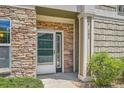 Close-up of front door with stone facade, and well-manicured bushes at 4385 S Balsam St # 6-103, Littleton, CO 80123
