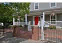 Inviting front porch featuring a vibrant red door, white pillars, lush landscaping, and brick accents, creating a warm entrance at 8171 E 33Rd Ave, Denver, CO 80238