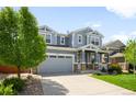 Attractive two-story home featuring blue siding, a two-car garage, a well-maintained lawn, and lush landscaping at 10057 Des Moines St, Parker, CO 80134