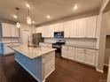 Bright, spacious kitchen featuring white cabinets, a granite island, stainless steel appliances, and modern lighting at 15861 E Otero Ave, Centennial, CO 80112