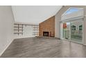 Living room with wood floors, exposed shelving, brick fireplace, and sliding door to balcony at 3337 S Monaco Pkwy # C, Denver, CO 80222