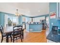 Open concept kitchen featuring white cabinets, blue walls, stainless appliances, and hardwood floors at 24022 E Jamison Dr, Aurora, CO 80016