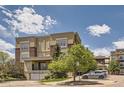 Modern exterior of a multi-story building with brick accents, a garage, and mature trees under a sunny blue sky with clouds at 5401 S Park Terrace Ave # 109A, Greenwood Village, CO 80111