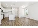 Bright, open-concept living area with hardwood floors, white walls, modern lighting, and an open kitchen at 6912 Huddersfield Ln, Castle Pines, CO 80108
