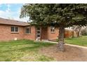 A well-maintained red brick house sits on a grassy lot, shaded by a large pine tree at 3700 Zenobia St, Denver, CO 80212