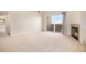 Bright living room with fireplace, plush carpet, and sliding doors to the balcony at 905 S Zeno Way # 204, Aurora, CO 80017