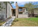 Charming exterior view of a multi-level condo with a stone chimney and well-maintained lawn at 7720 W 87Th Dr # J, Arvada, CO 80005