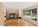 Bright living room featuring a stone fireplace, hardwood floors, and large windows at 6338 S Oneida Ct, Centennial, CO 80111