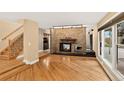Open-concept living room with a stone fireplace, hardwood floors, and staircase at 6338 S Oneida Ct, Centennial, CO 80111