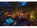 Backyard deck featuring a hot tub, string lights, tennis court and outdoor fire pit seating area at 33208 Alta Vista Dr, Evergreen, CO 80439