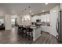 Modern kitchen features white cabinets, pendant lighting, and island with seating at 8230 S White Crow St, Aurora, CO 80016