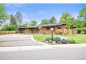 Charming red brick home with landscaped yard, bright orange door and attached garage at 5200 W Rowland Ave, Littleton, CO 80128