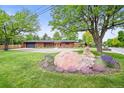 Stunning front exterior of a red brick home with mature landscaping and orange front door at 5200 W Rowland Ave, Littleton, CO 80128