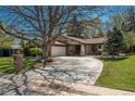 Inviting single-story home with mature trees, brick detailing, and a spacious driveway at 5000 S Chester St, Greenwood Village, CO 80111