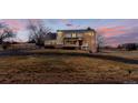 Charming two-story home featuring a brick turret under a sunset with mature landscaping at 7208 Secrest Ct, Arvada, CO 80007