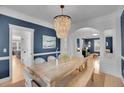 Elegant dining room featuring a rustic table, stylish chandelier, blue walls, and an open view to the living room at 3212 Fulton St, Denver, CO 80238