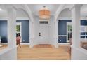 Bright and airy foyer with white columns, light hardwood floors, elegant lighting, and a view to the dining room at 3212 Fulton St, Denver, CO 80238