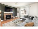 Cozy living room featuring a stone fireplace, large window, and comfortable sectional sofa at 3567 E 140Th Dr, Thornton, CO 80602