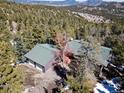 An aerial shot shows the home with mountain views and lots of trees at 11540 Inspiration Rd, Golden, CO 80403