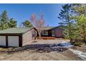 Charming home exterior with a two-car garage, inviting front porch, and wooded surroundings at 11540 Inspiration Rd, Golden, CO 80403