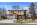 Two-story home with a blend of yellow siding and brick, complemented by a well-maintained front lawn and mature trees at 3680 S Pontiac Way, Denver, CO 80237