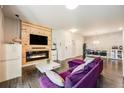 Cozy living room features a modern fireplace, mounted TV, dining area, and comfortable purple couch at 15345 W 64Th Ln # 201, Arvada, CO 80007