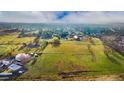 Wide aerial shot showing vast green acreage with scattered buildings, trees, and a community visible in the background at 5800 W Bowles Ave, Littleton, CO 80123
