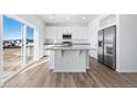 Contemporary kitchen with white cabinets, stainless steel refrigerator and center island, and wood-look flooring at 3908 N Riviera Ct, Aurora, CO 80019