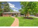 Charming ranch-style home with brick accents, lush lawn, and a brick walkway leading to the front door at 423 Nile St, Aurora, CO 80010