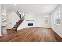 Open living room featuring hardwood floors, stairs to second floor, and modern fireplace at 5614 Riverbend Ave, Firestone, CO 80504