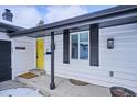 Close-up of a home's entry showing a vibrant yellow front door, modern black accents, and a well-kept porch at 3091 S Krameria St, Denver, CO 80222