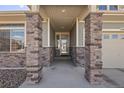 Inviting front porch featuring substantial stone columns, neutral siding and a glass front door at 20162 E 53Rd Pl, Denver, CO 80249