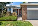 Inviting front entrance with a brick accent wall, a well-maintained lawn, and mature landscaping at 11 Canongate Ln, Highlands Ranch, CO 80130