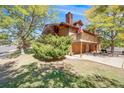 Charming exterior view showcasing the home's balcony, brick accents, mature trees and a lush green lawn at 1810 Youngfield Ct # A, Golden, CO 80401