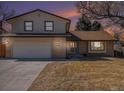 Charming brick and siding home at twilight featuring an attached garage, mature trees, and well-maintained lawn at 6527 S Ammons Ct, Littleton, CO 80123