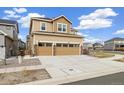 Tan two-story home featuring a two-car garage with a driveway and a patch of grass on the side at 10913 Ledges Rd, Parker, CO 80134