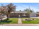 Charming brick home with well-maintained lawn, mature trees, and a walkway leading to the front door at 1568 S Dudley Ct, Lakewood, CO 80232