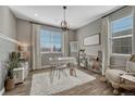 Bright home office with a modern desk, shelving, large windows, and a comfortable sitting area at 11796 Edenfeld St, Parker, CO 80134