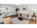 Bright living room with wood-look flooring, light gray sofa, neutral rug, and large window providing natural light at 1457 S Pierce St, Lakewood, CO 80232