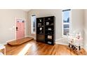 Inviting entryway featuring a pink front door, hardwood floors, and a dark wood bookshelf with stylish decor at 7155 E Exposition Ave, Denver, CO 80224
