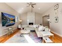 Bright living room with a fireplace, large sectional sofa, a ceiling fan, and wood floors at 7155 E Exposition Ave, Denver, CO 80224