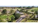 Aerial view of house with a two-car garage, set amidst green rolling hills and scattered trees at 7388 S Ireland Cir, Centennial, CO 80016
