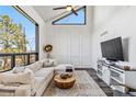 Modern living room with a large window, vaulted ceiling, white sectional sofa, and stylish decor at 7388 S Ireland Cir, Centennial, CO 80016