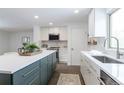 Well-lit kitchen with stainless steel appliances, white cabinets, quartz countertops, and a dark green island at 6526 S Cherry Way, Centennial, CO 80121