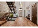 Inviting home foyer with hardwood floors, high ceilings, custom metal stairs, and a large wood front door at 2466 Spruce Meadows Dr, Broomfield, CO 80023