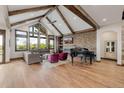 Open living area with vaulted ceilings, wood beams, stone accent wall, piano, and large windows at 2466 Spruce Meadows Dr, Broomfield, CO 80023
