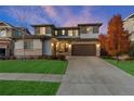 Dusk view of a home with manicured lawn, stone accents and an attached two-car garage at 515 Orion Ave, Erie, CO 80516
