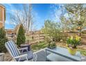 Backyard featuring a cozy patio setup with a blue chair and table, surrounded by lush greenery and a wooden fence at 19691 E 59Th Dr, Aurora, CO 80019