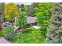 Lush backyard oasis featuring a patio, mature trees, and expansive lawn at 2473 S Carr Ct, Lakewood, CO 80227