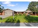 Well-maintained home featuring a manicured lawn, mature trees, and brick exterior at 92 S Devinney St, Golden, CO 80401